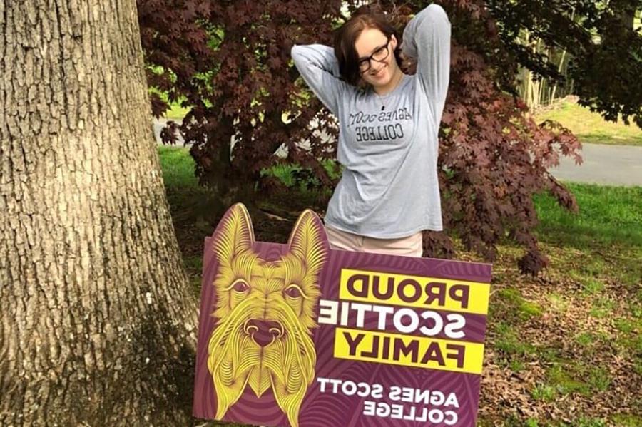 student standing behind Scottie pride yard sign